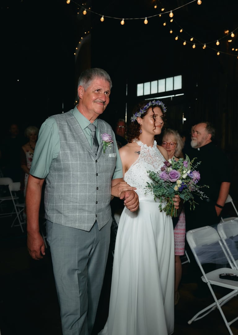 A father and a bride walking down a aisle in a barn wedding