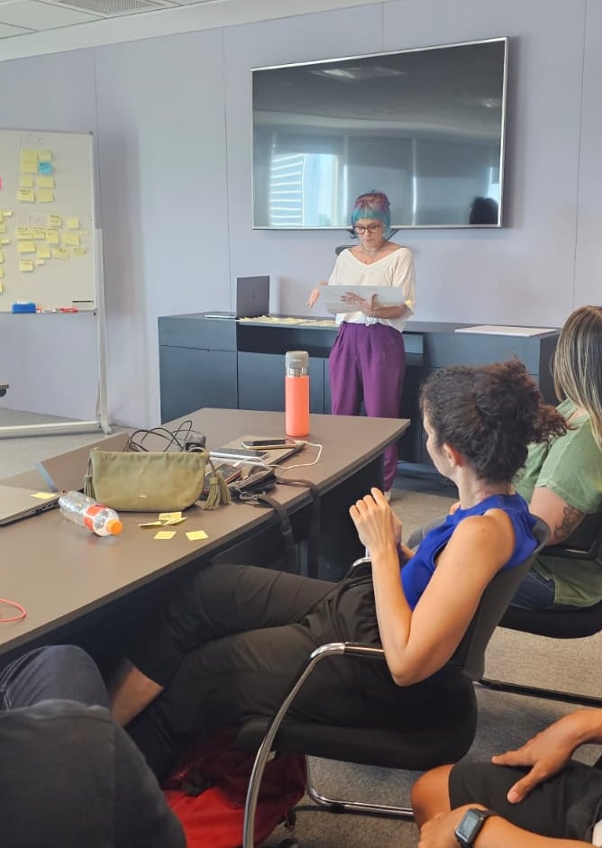 Gabriela Bechara Zillig conduz dinâmica de Design Sprint em uma sala de reunião para colegas