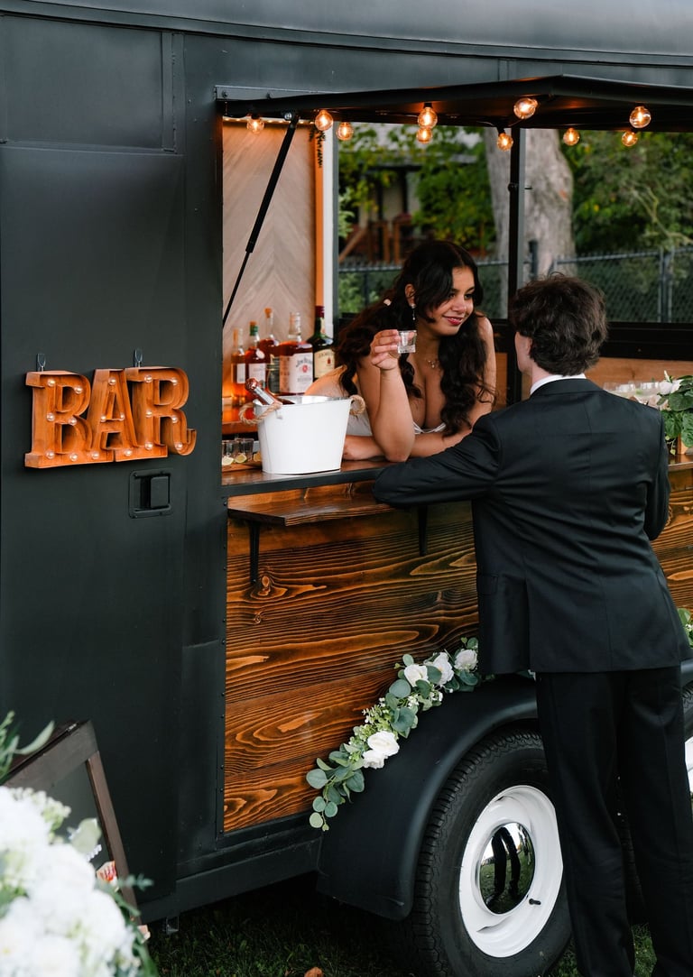 a bride and groom standing in front of our mobile trailer bar