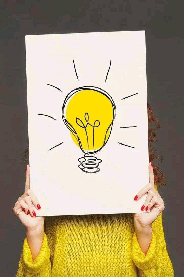 Persona que sostiene una bombilla que dibuja en un cartel y representa una idea creativa