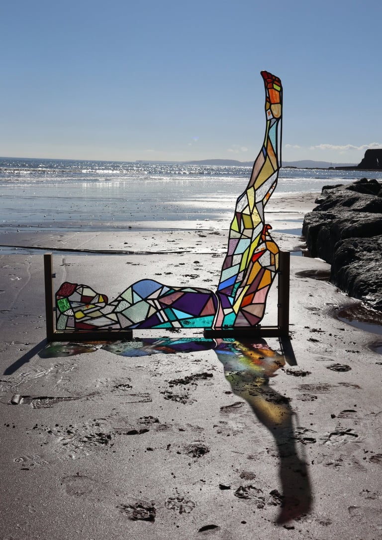 Full Sized Stained Glass Woman. Photograph is taken on a beach at low tide. Art work by Laura Kriefman