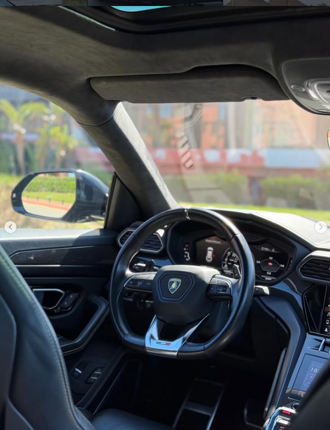 Interior view of a luxury Lamborghini Urus featuring a leather steering wheel and digital dashboard.