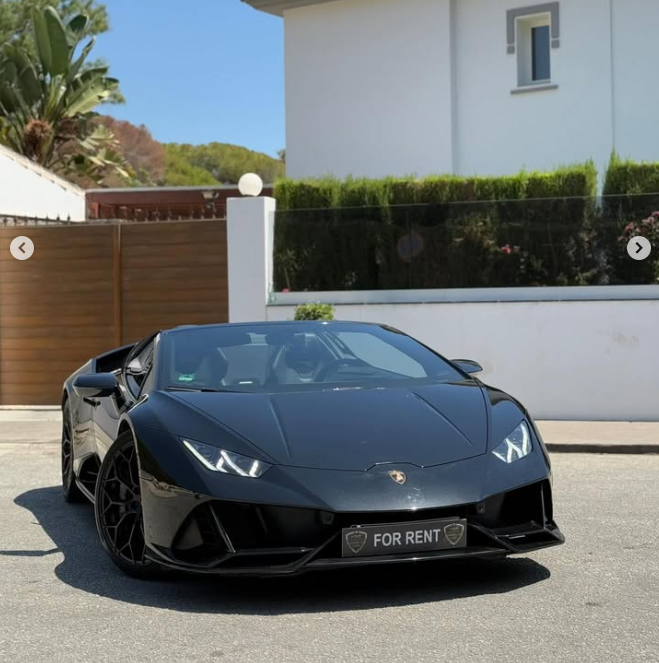 Luxury black Lamborghini Huracan available for exotic car rental parked in front of a modern villa.