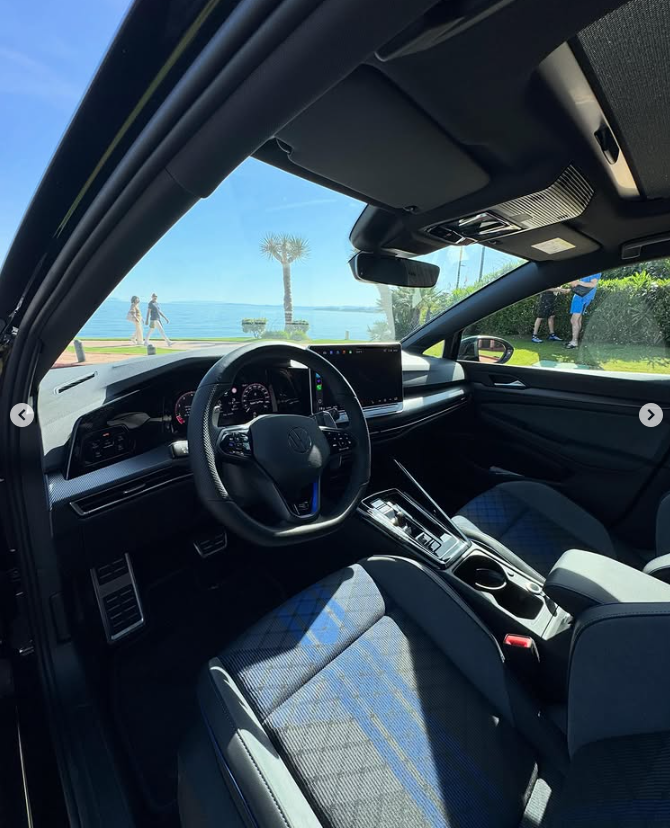 Modern Volkswagen Golf interior featuring a digital cockpit and blue sport seats parked by the sea.