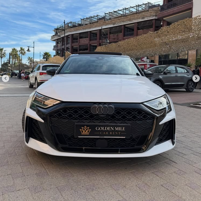 Front view of a white Audi luxury rental car parked on a cobblestone street at Golden Mile Car Rent.