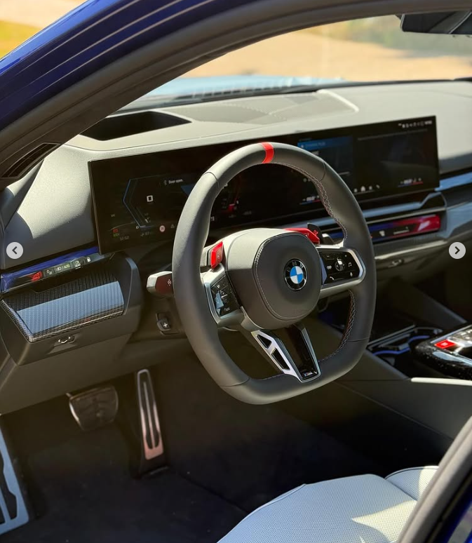 Interior view of a modern BMW M performance car featuring a digital dashboard and leather steering wheel.
