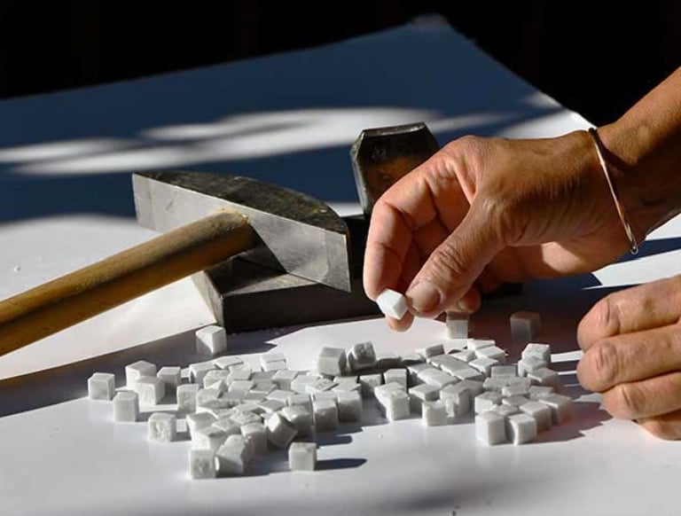 a person is using a hammer hammer to make a block of white cubes