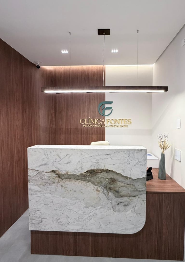 Recepção de clínica médica moderna com balcão em mármore, painéis de madeira e o logotipo da Clínica
