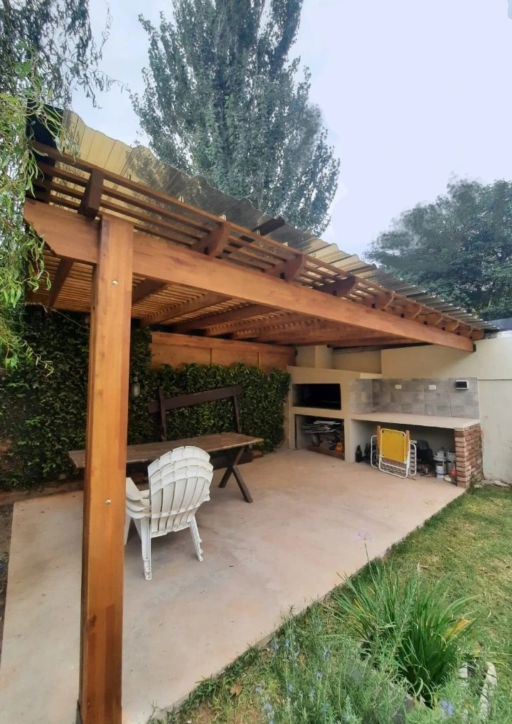 Patio rústico al aire libre con pérgola de madera con techo de chapa ondulada.