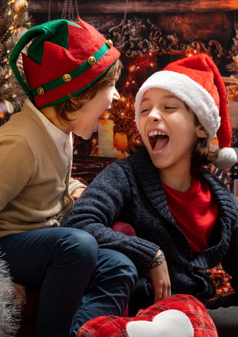 2 boys sitting on a couch in a christmas tree