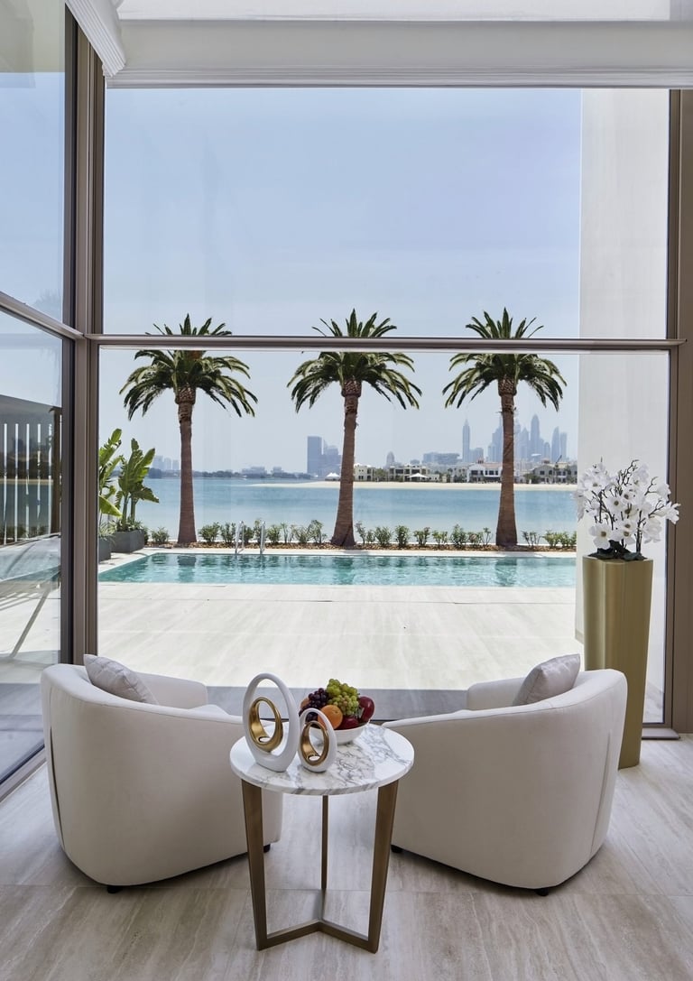 Luxury villa interior overlooking a private pool, palm trees, and the Dubai Marina skyline.