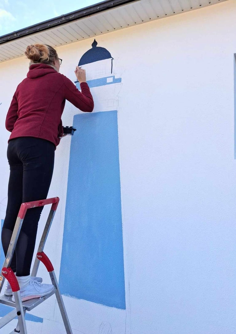 Artiste en train de peindre une fresque bleue sur un mur de maison