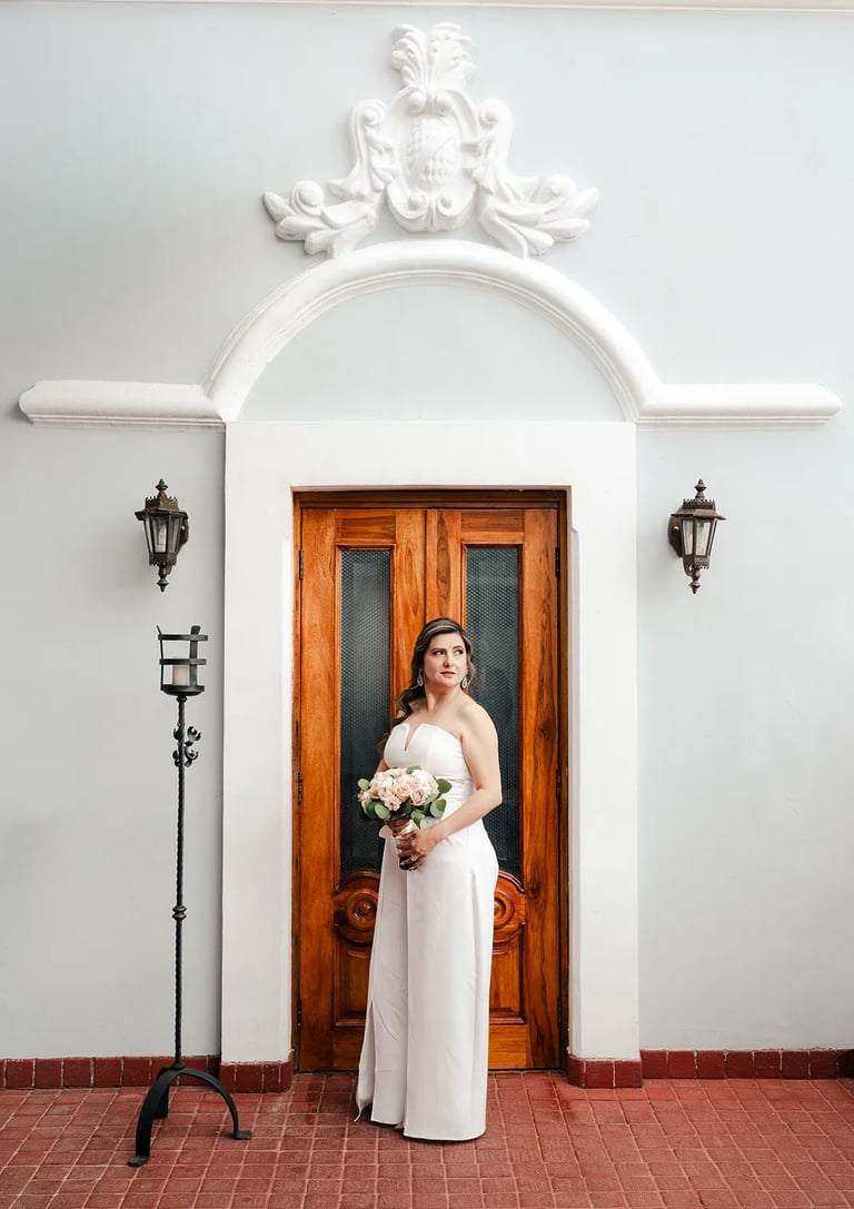 Novia en el día de su boda posando elegante con su ramo de flores en el centro histórico de Quito