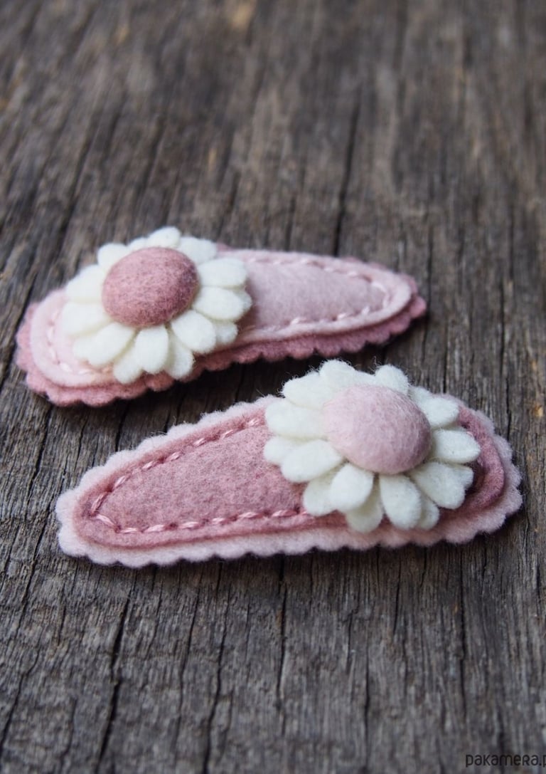 różowe spinki z białym kwiatkiem na tle drewnianej deski