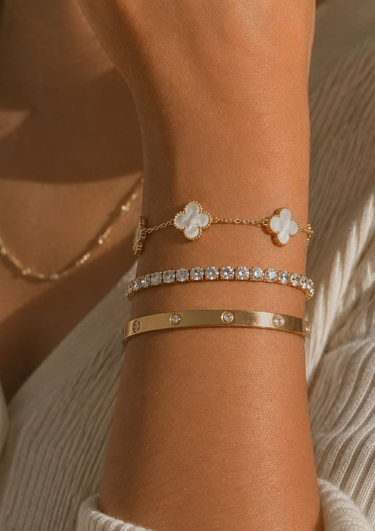Three gold bracelets styled on a beige stone surface with soft natural lighting