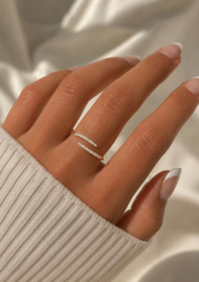 Close-up of a gold crystal open ring worn on a hand with a soft cream sweater sleeve.