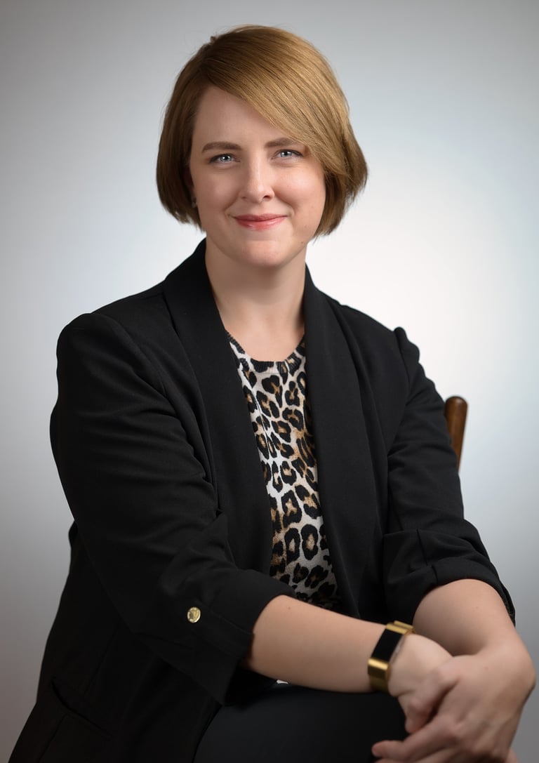 a woman in a black jacket and leopard print top sitting in front of a white background