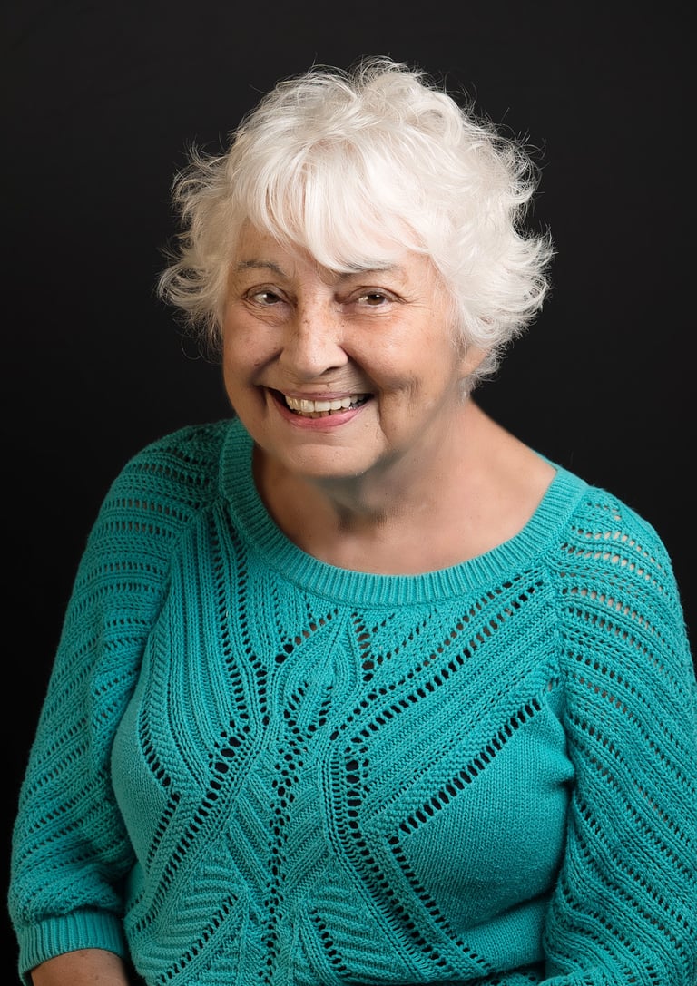 a woman with white hair and a blue sweater with big smile