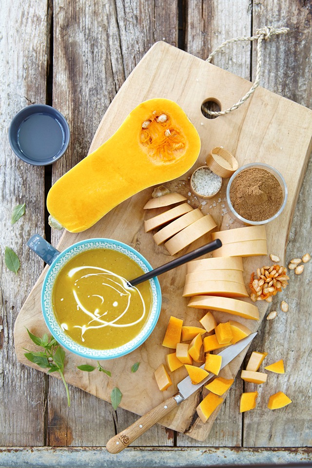 a wooden cutting board with a bowl of soup and a knife