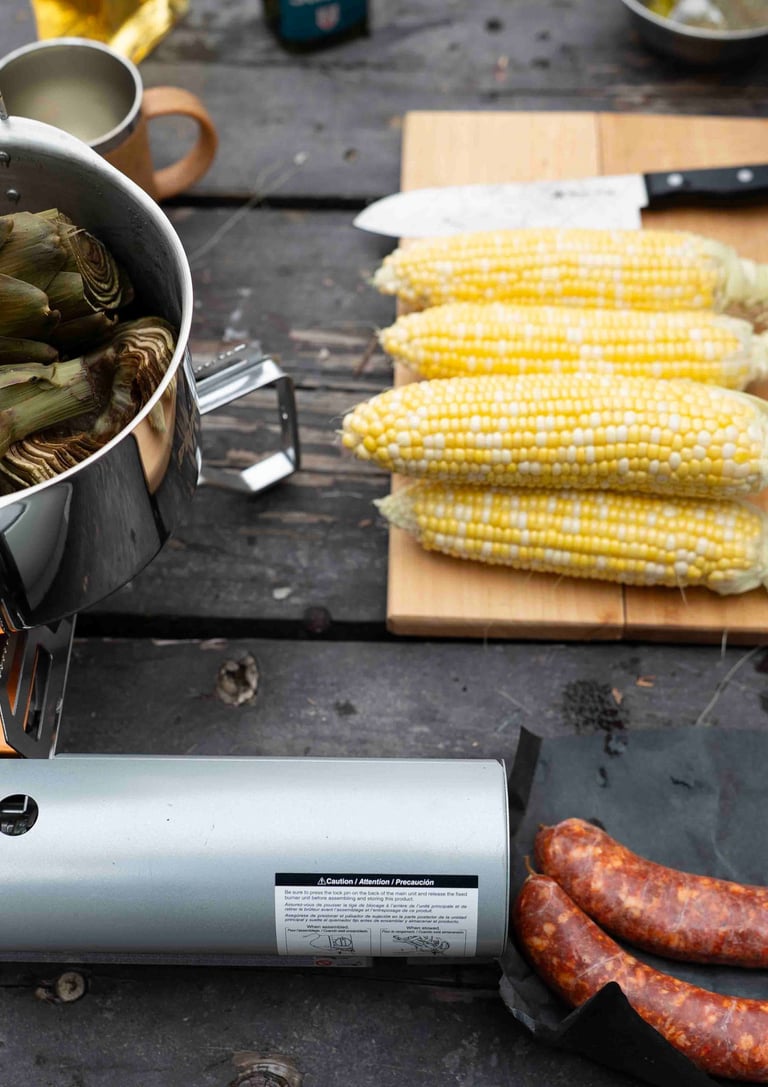 Artichokes cooking in a pot with corn of a cutting board