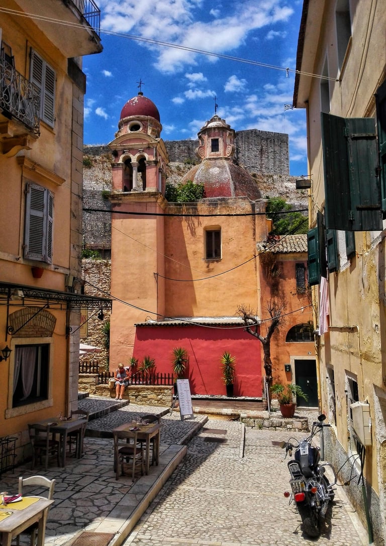 a motorcycle parked in a narrow alley with a red wall