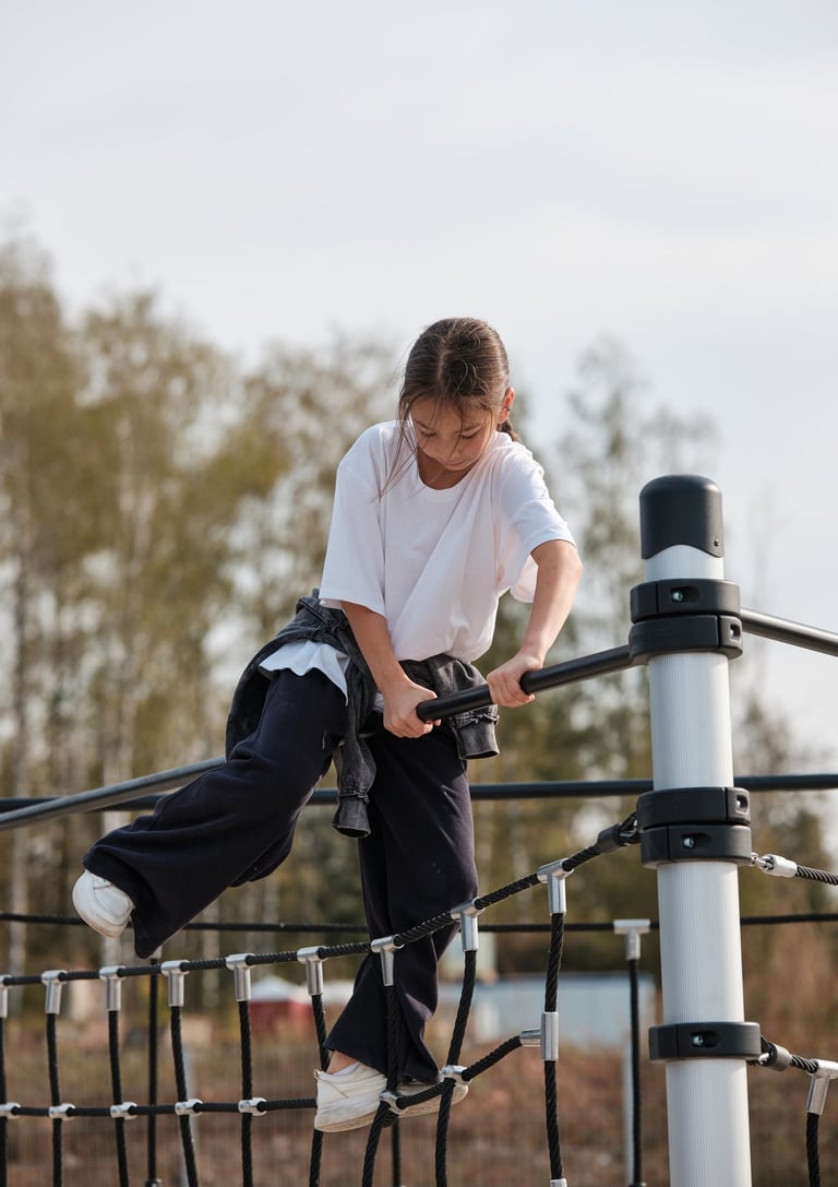 Fille grimpant sur une structure Kenguru Pro Kids Active Play en extérieur.