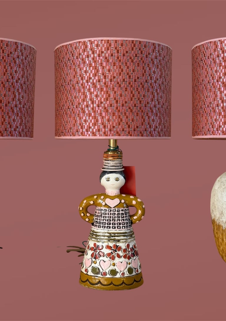 Three unique mid-century modern ceramic table lamps with pink patterned lampshades on a mauve background.