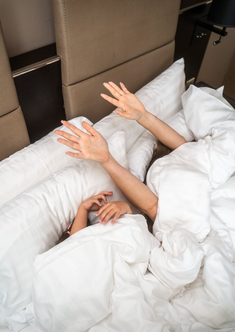 Maman et sa fille sous la couette dans une chambre d'hôtel