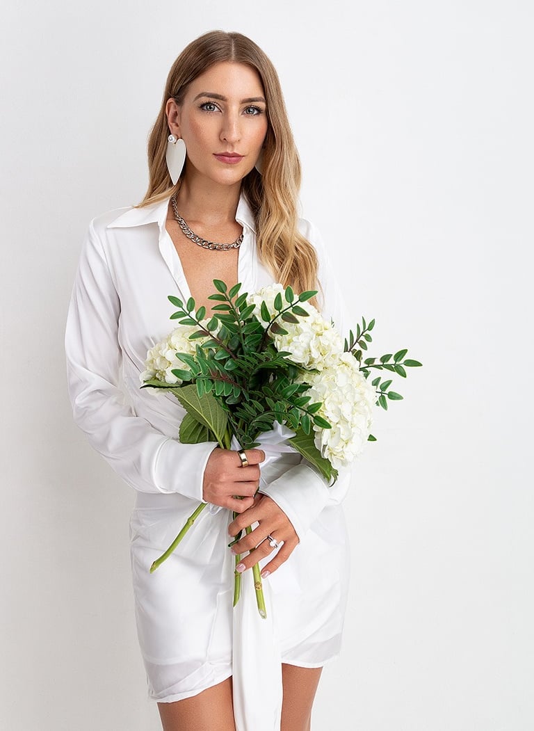 a woman in a white shirt and a necklace with flowers