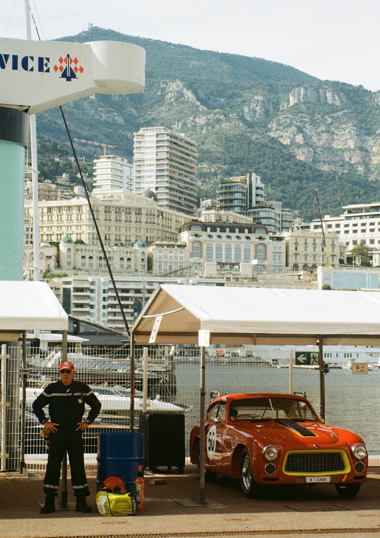 a race car parked in the paddock with a man stood next to it