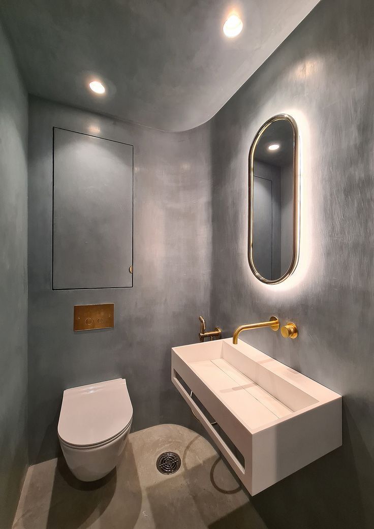 A modern bathroom with walls finished in blue Venetian microcement, a white trough-shaped washbasin