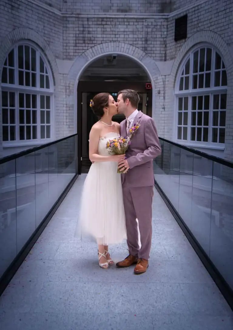 A bride in a white tulle dress and a groom kissing on the internal bridge, Lambeth Town Hall