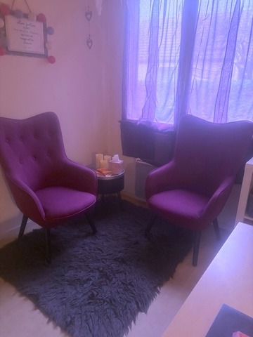 a living room with a purple chair and a black rug