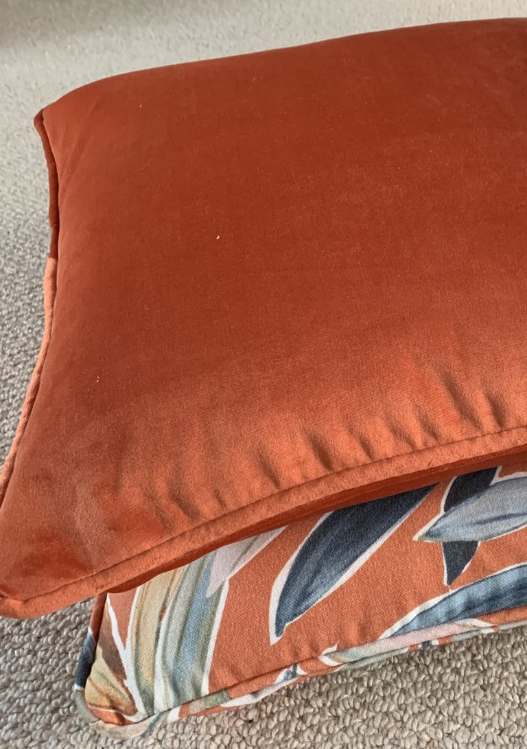 2 coordinated piped cushions with dominant colour in burnt orange