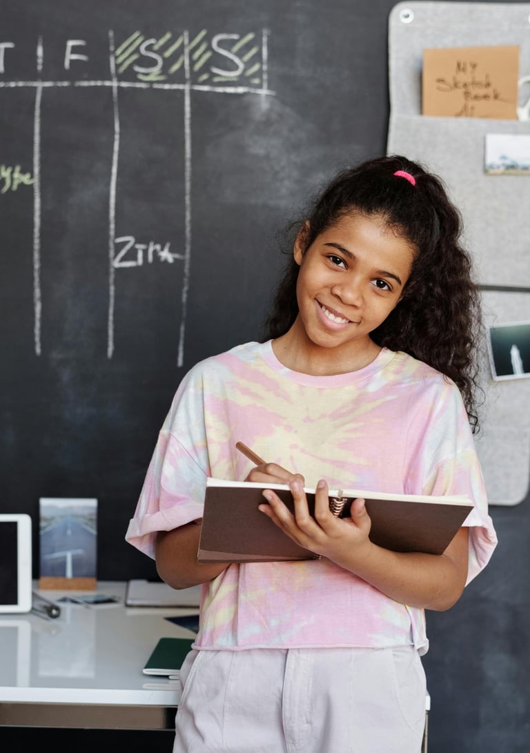 Menina adolescente sorridente segurando um caderno e lápis em frente a um quadro negro com cronograma semanal organizado