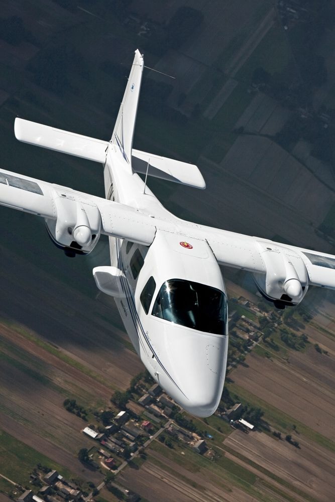 a white airplane flying over a field