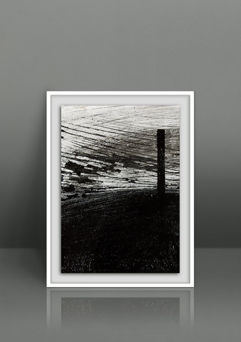 Framed minimalist black and white abstract art print with textured brushstrokes on a gray wall.