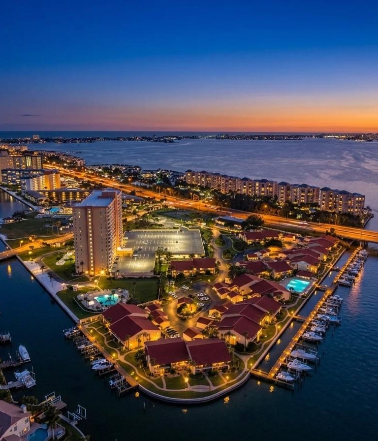 Aerial view of luxury waterfront condos and a marina at sunset in Clearwater, Florida.