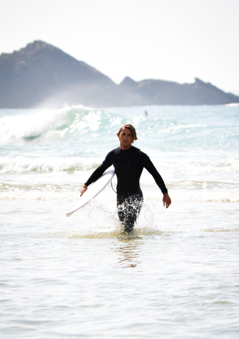 a man in a wetsuit is holding a surfboard
