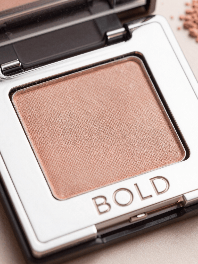Close-up of a luxurious serum bottle with a sleek gold cap resting on a marble surface.