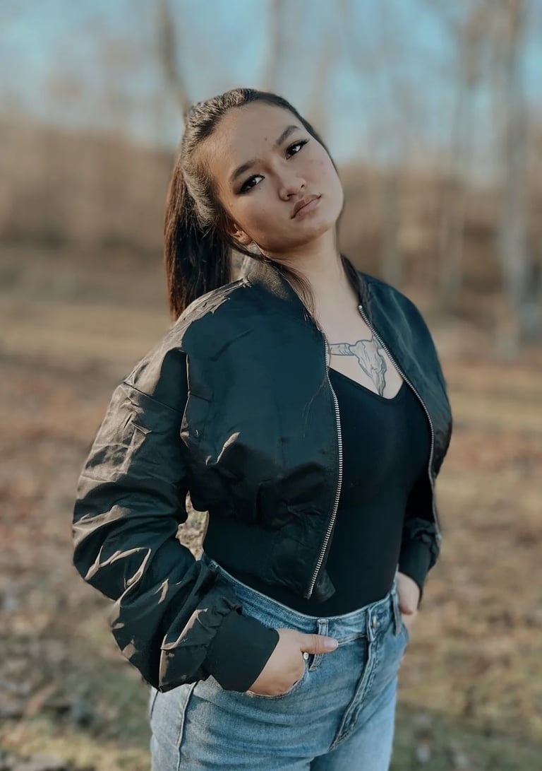 Woman in a black top with a jacket on and jeans