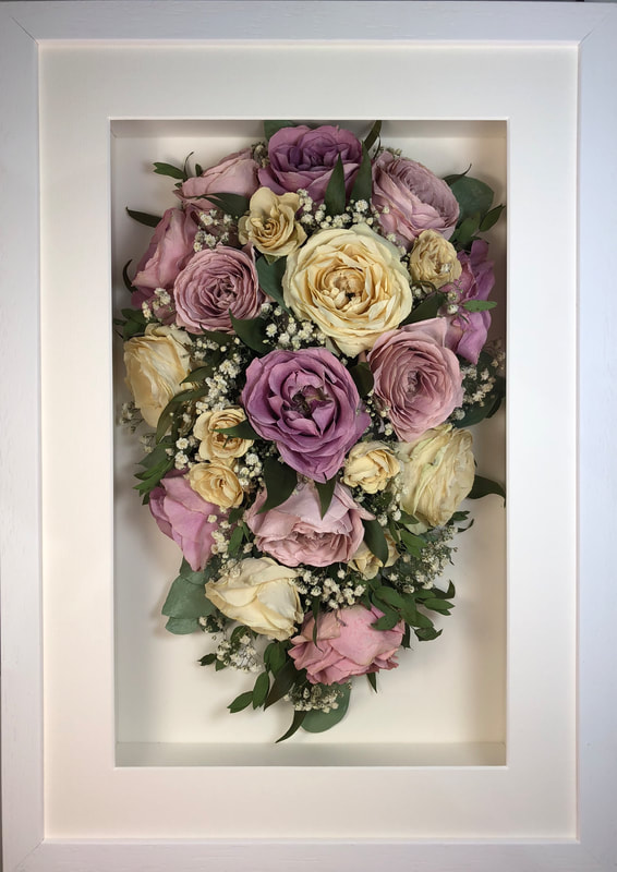 a trailing view Style bouquet of flowers in a thick white frame