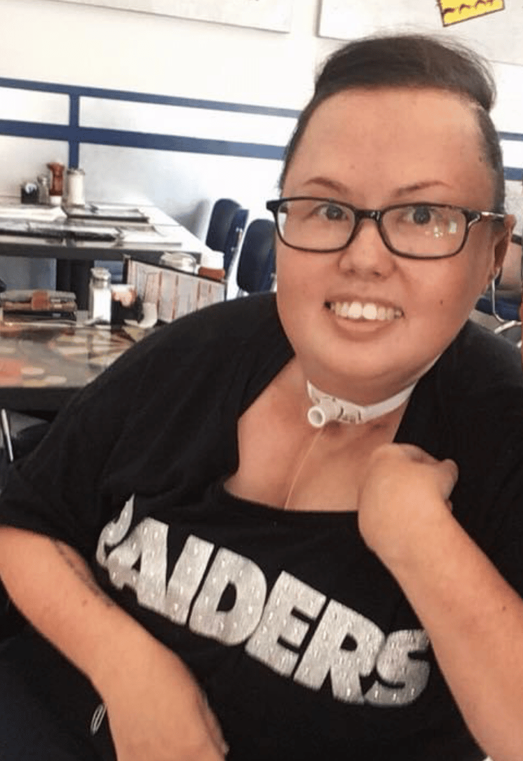 Photo of Stacey with hair pulled back and smiling with a Raiders tee shirt.