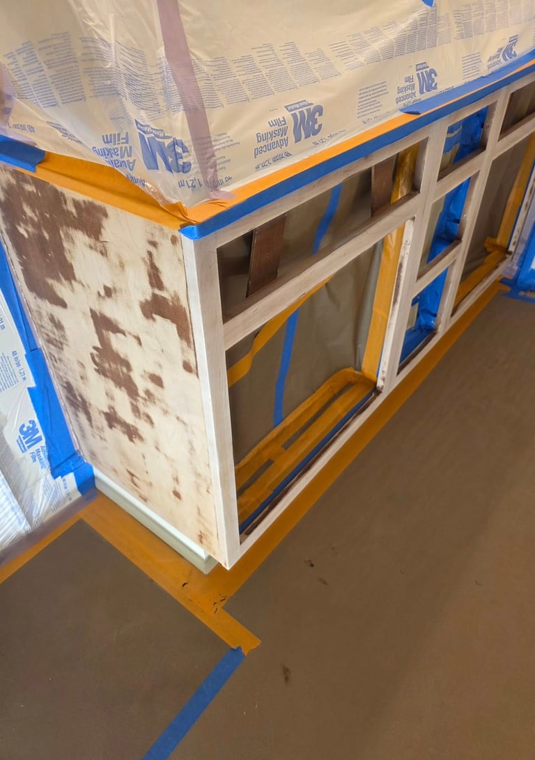 Sanded kitchen cabinets prepared for painting with 3M masking film and blue painter's tape.