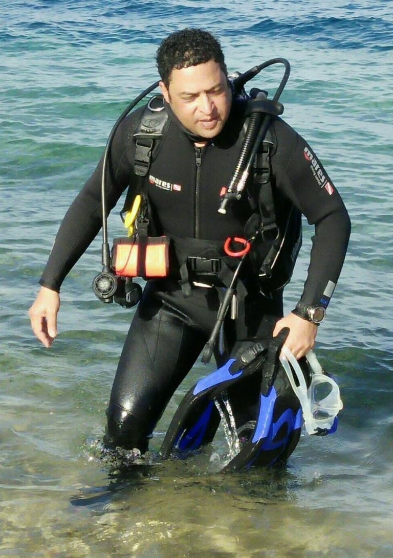 Captain Essam in a wetsuit is standing in the water