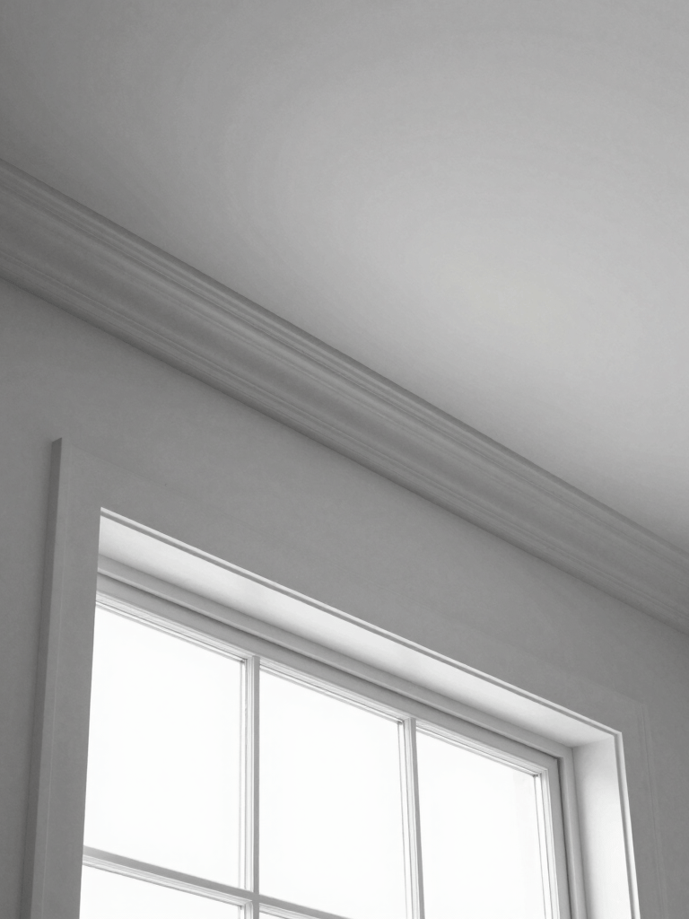 Close-up of elegant white crown molding framing a cozy living room ceiling.