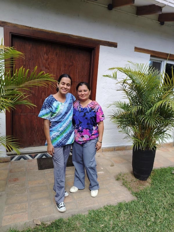 two women standing in front of a house