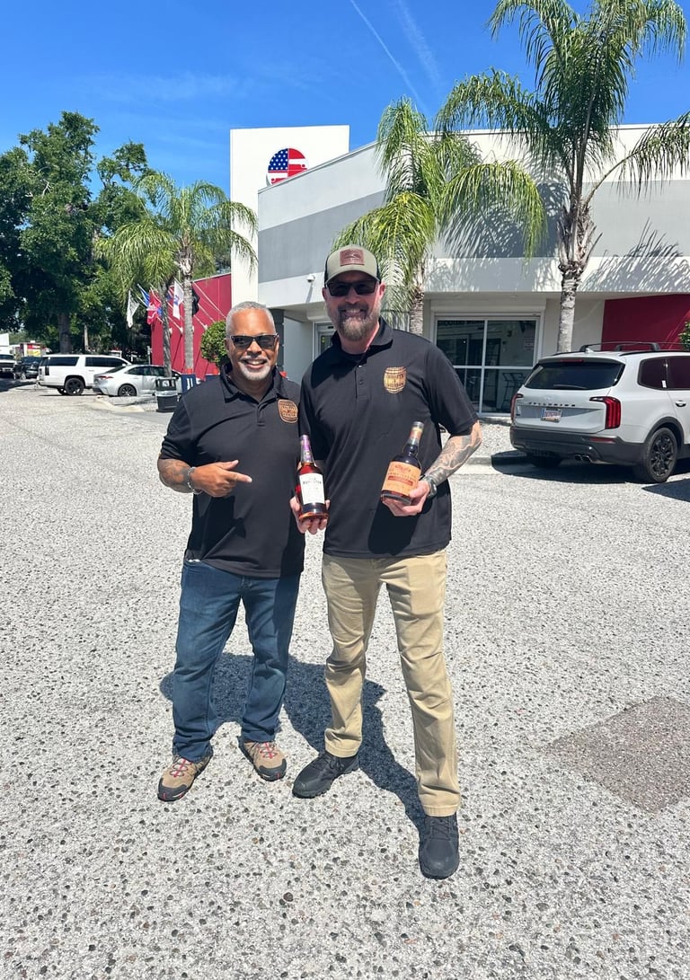 two men wearing bullets and bourbon polos holding two different bottles of bourbon