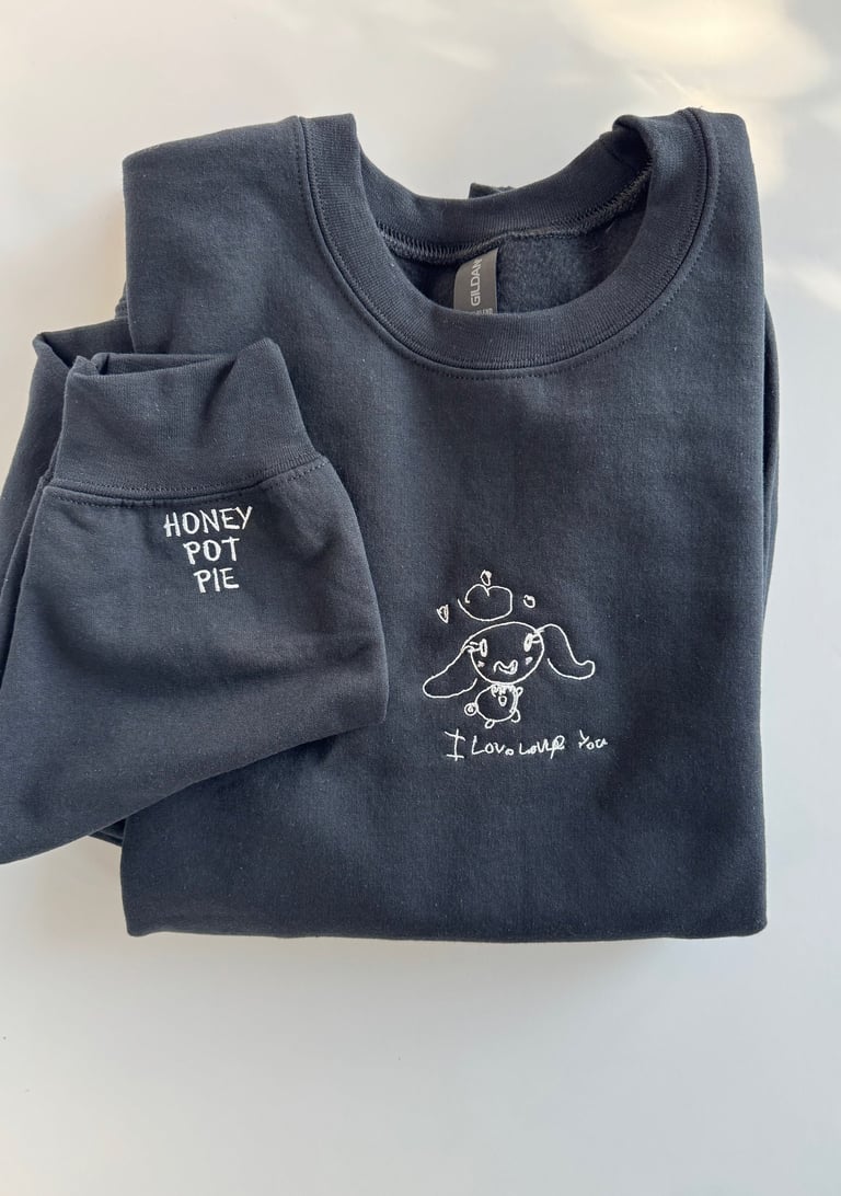 a black sweatshirt with a child's drawing embroidered on it