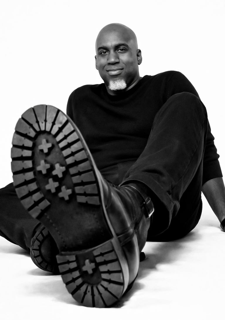 Lee A Jones in all black sitting on the floor with black boots